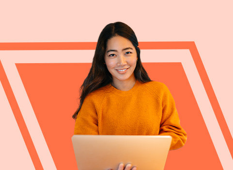 girl in orange sweatshirt with laptop on peach background.