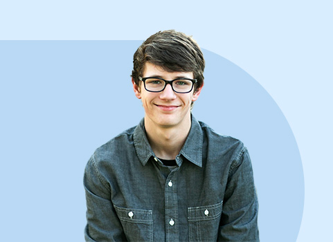 Boy in button up shirt and glasses smiling.