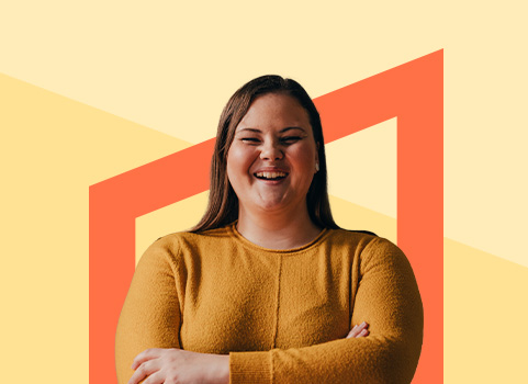 Girl in yellow sweater smiling in front of orange background.