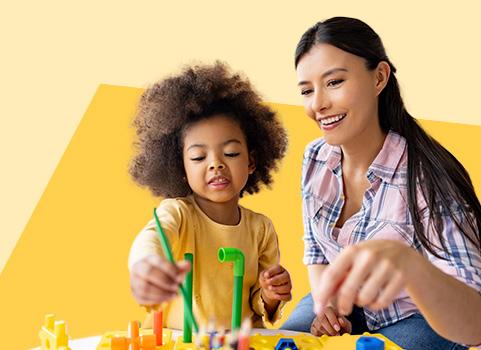 woman and small child playing with an activity table on yellow background.