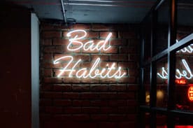A Neon sign that displays the words "bad habits"