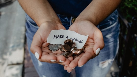 person holding coins with paper that says make a change