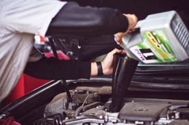 Auto Repair Technician performing an oil change on a vehicle.