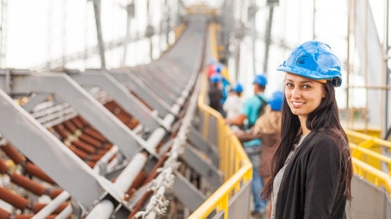 Woman wearing a hard hat overseeing manufacturing & construction