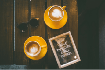 Two coffee mugs on a table with a self-help book.