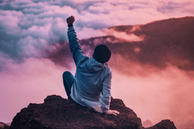 Confident person watching the sunset from atop a mountain.