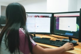 woman work on dual screen desktop computers.