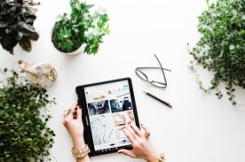 person using tablet on white desk.