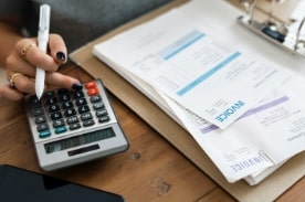 woman using calculator with invoices