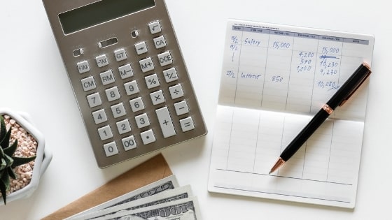 calculator, checkbook, and money on white surface