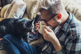 man drinking coffee with cat