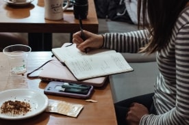 woman taking notes in cafe.