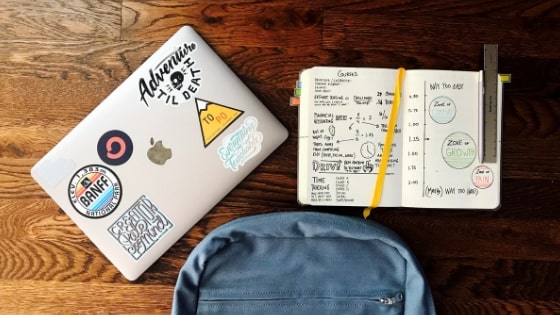 backpack, laptop, and notebook on table.