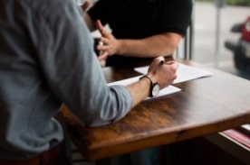 man filling out paper during interview.