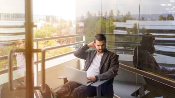 A man working on a computer on a balcony.