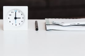 clock with pen and notebook on desk