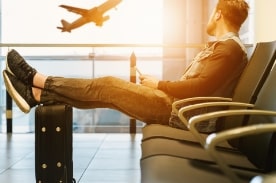 man in airport watching plane take off.