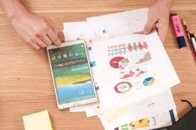 Person looking over financial paperwork with tablet.