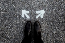 person standing on pavement with two white arrows.