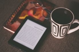 ereader and notebook on desk.