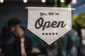 sign with text 'yes, we're open' on door.