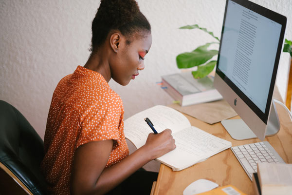 Woman taking notes at desk.