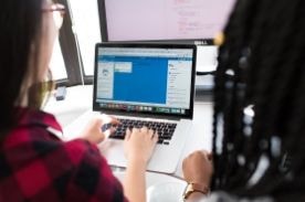two women using laptop.