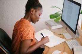 woman writing in notebook.