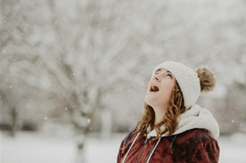 Girl looking up at falling snow.