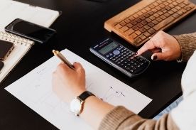 woman using calculator and taking notes.