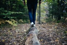 Person walking on log in forest.