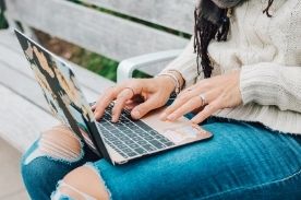 girl using laptop on park bench.