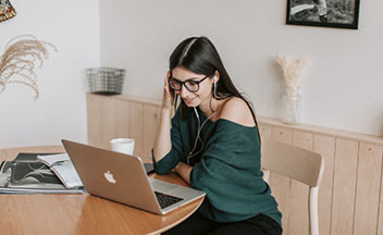 girl sitting in front of laptop with earphones.