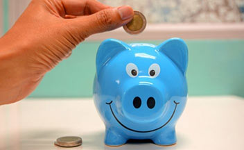 person putting coin into piggy bank.