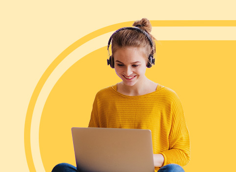 girl in yellow sweater with headphones using a laptop on yellow background.