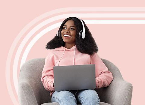 Girl in pink hoodie with headphones using laptop.
