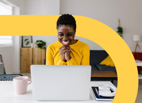 woman in yellow sweater smiling at laptop.