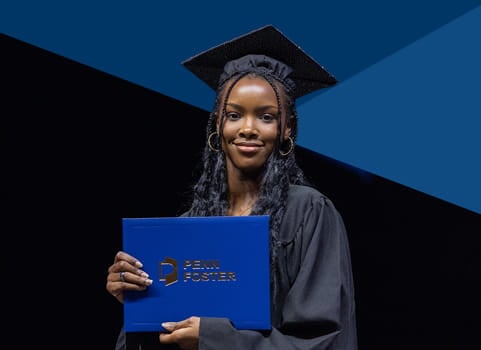 Penn Foster graduate in cap and gown holding diploma.