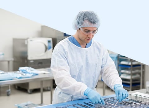 Man in scrubs and PPE arranging tools for surgery.
