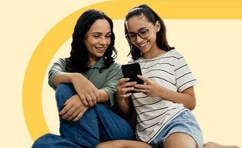 mom and daughter smiling looking at cell phone.