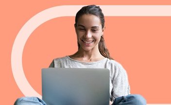 student with silver laptop smiling.