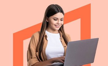 girl using silver laptop on orange background.