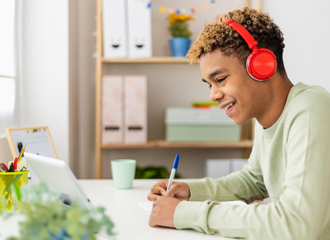 A student wearing headphones smiles at a tablet