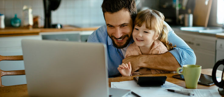father and daughter looking at laptop smiling.