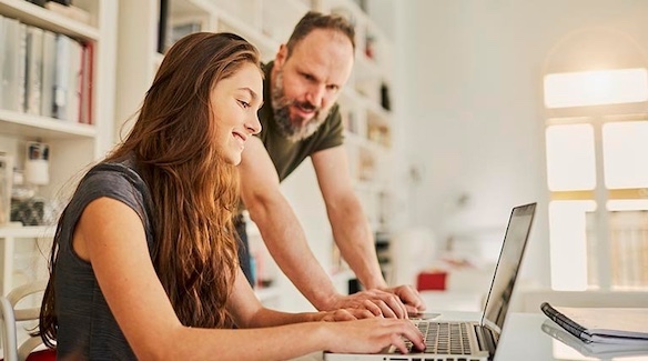 parent watching teen daughter on laptop.