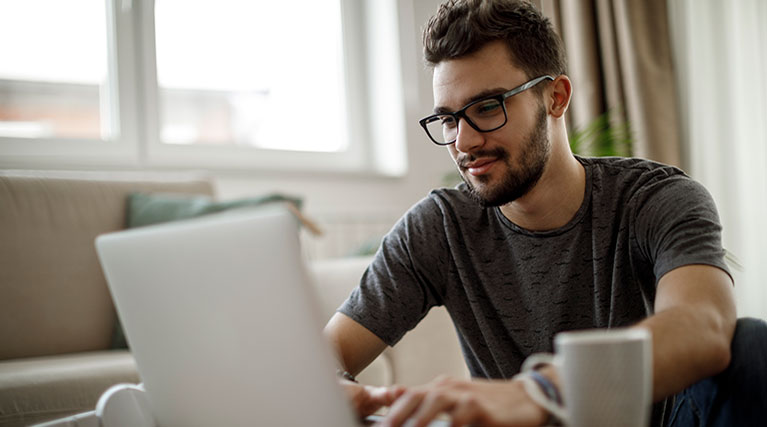 Male high school student studying at home on a laptop.