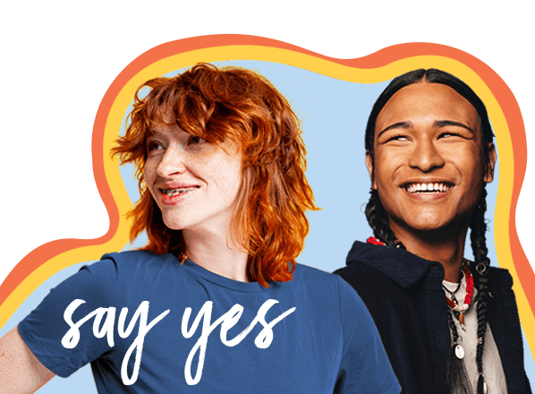 Two people smiling, one with red hair wearing a blue shirt, the other with long dark hair and a necklace. The words "say yes" are written in white script across the image.