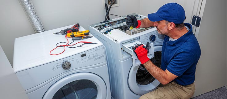 appliance repair technician fixes laundry machine.