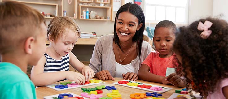 early childhood educator sitting with students.