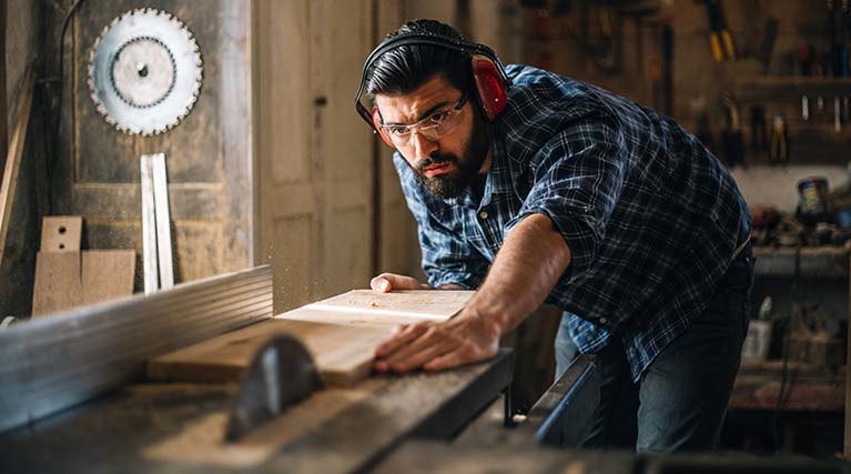 man doing woodwork with a saw.